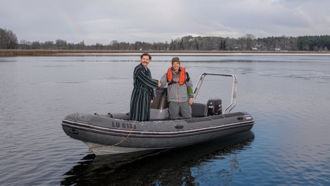 2 cilvēki uz ezera laivā sarokojas
